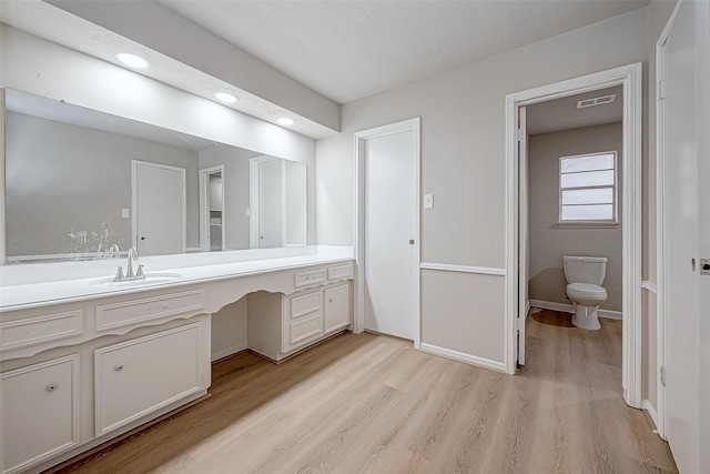 bathroom with toilet, wood finished floors, visible vents, vanity, and baseboards