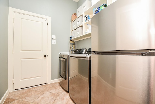 laundry room featuring laundry area, light tile patterned floors, baseboards, and separate washer and dryer