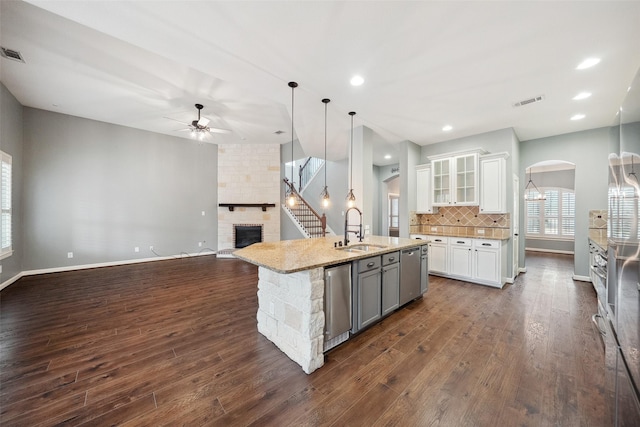 kitchen featuring tasteful backsplash, stainless steel dishwasher, a large fireplace, open floor plan, and a sink