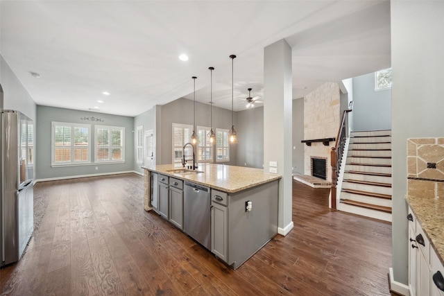 kitchen featuring stainless steel appliances, open floor plan, a sink, and gray cabinetry