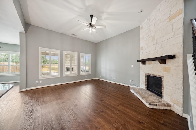 unfurnished living room featuring dark wood-type flooring, a fireplace, a ceiling fan, and baseboards