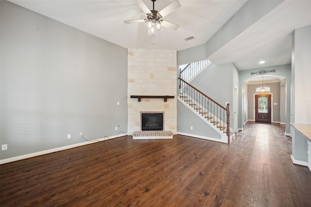 unfurnished living room with dark wood-style flooring, a fireplace, stairway, a ceiling fan, and baseboards