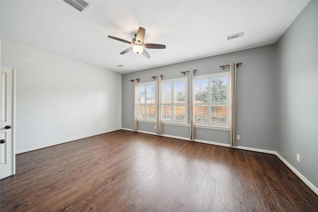 spare room featuring visible vents, ceiling fan, baseboards, and wood finished floors