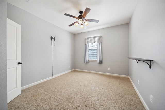 carpeted spare room featuring baseboards and a ceiling fan