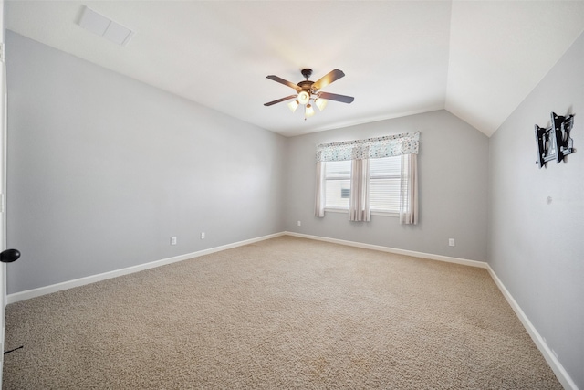 spare room with lofted ceiling, light colored carpet, visible vents, a ceiling fan, and baseboards