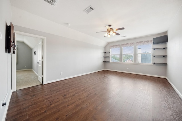 empty room featuring vaulted ceiling, ceiling fan, dark wood-style flooring, and visible vents