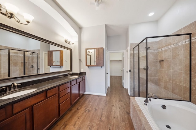 full bath featuring wood finished floors, a sink, a shower stall, and a bath