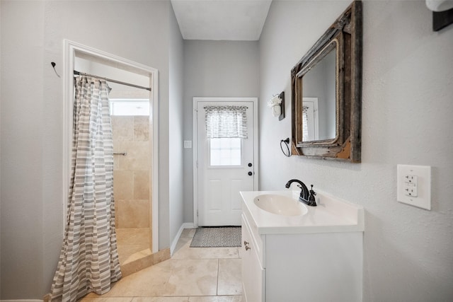 bathroom featuring tile patterned floors, a tile shower, and vanity