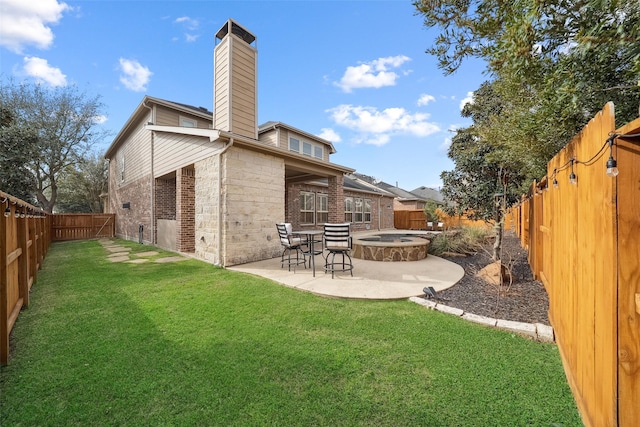 back of house featuring a patio, a yard, a chimney, and a fenced backyard