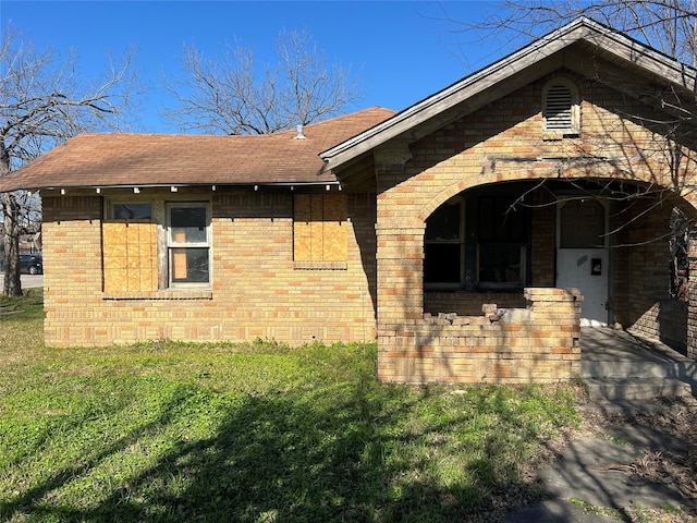 exterior space featuring brick siding and roof with shingles