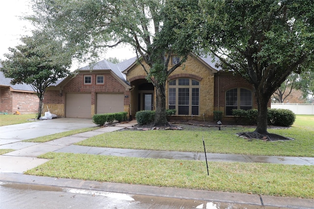 traditional-style house featuring a garage, brick siding, concrete driveway, stone siding, and a front yard