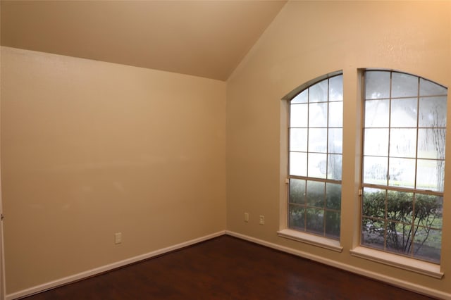 spare room with vaulted ceiling, dark wood finished floors, and baseboards