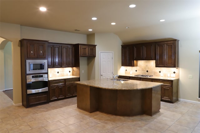 kitchen with arched walkways, appliances with stainless steel finishes, backsplash, and a sink