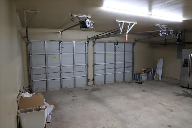 garage with a garage door opener and stainless steel fridge with ice dispenser