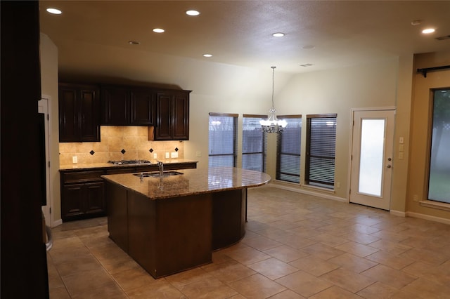 kitchen with a sink, light stone countertops, a chandelier, backsplash, and recessed lighting