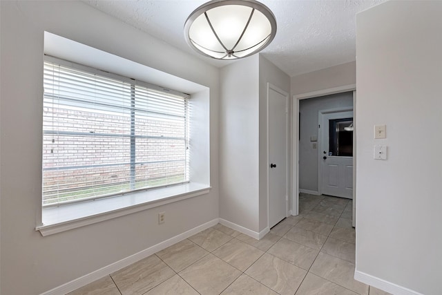 spare room with baseboards and a textured ceiling