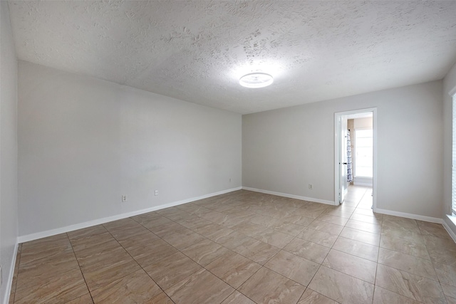 empty room with a textured ceiling and baseboards