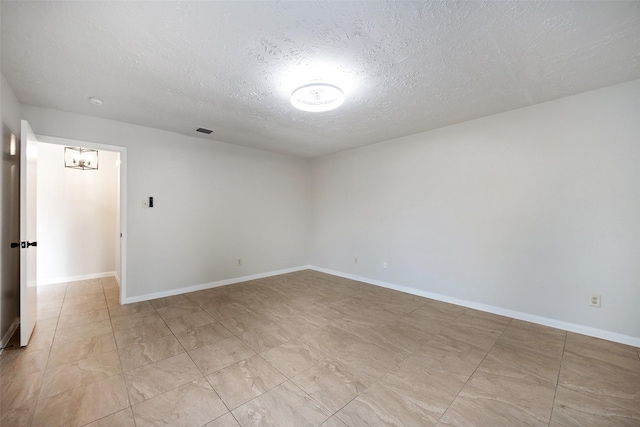 unfurnished room with visible vents, baseboards, and a textured ceiling