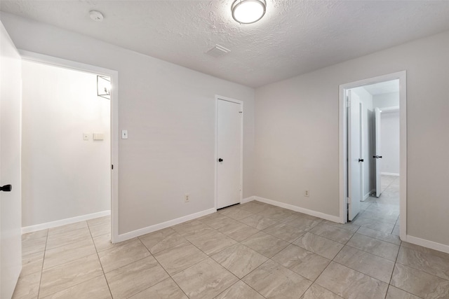 spare room with visible vents, a textured ceiling, and baseboards