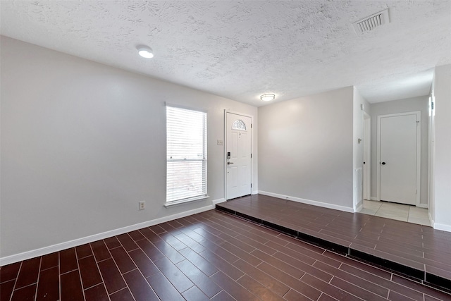 entrance foyer with baseboards, a textured ceiling, visible vents, and wood finished floors