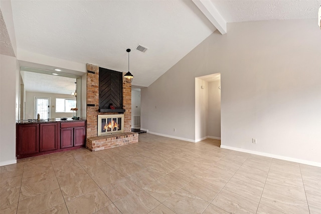 living area with beam ceiling, a fireplace, visible vents, and baseboards