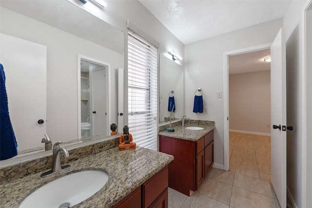 full bath with tile patterned flooring, two vanities, a sink, and baseboards