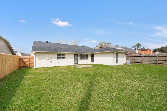 rear view of property featuring a fenced backyard, a yard, and stucco siding