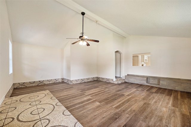 empty room with arched walkways, a ceiling fan, wood finished floors, high vaulted ceiling, and beam ceiling