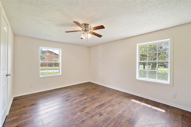 empty room featuring a textured ceiling, dark wood-type flooring, plenty of natural light, and baseboards