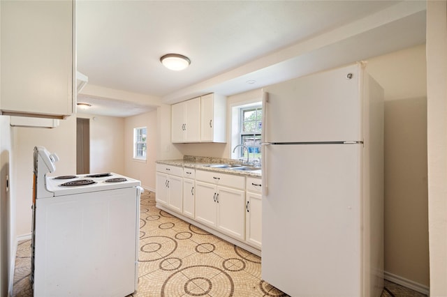 kitchen with white appliances, baseboards, white cabinets, light countertops, and a sink