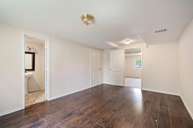 spare room featuring baseboards, visible vents, and wood finished floors