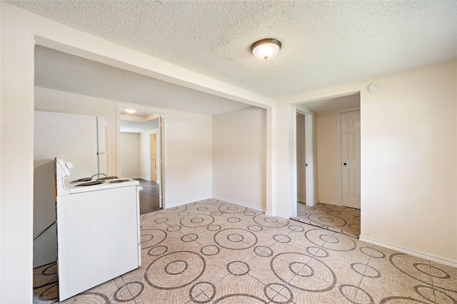 empty room with a textured ceiling and baseboards