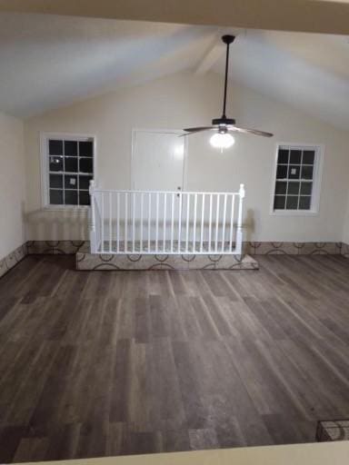 empty room featuring ceiling fan, lofted ceiling with beams, baseboards, and wood finished floors