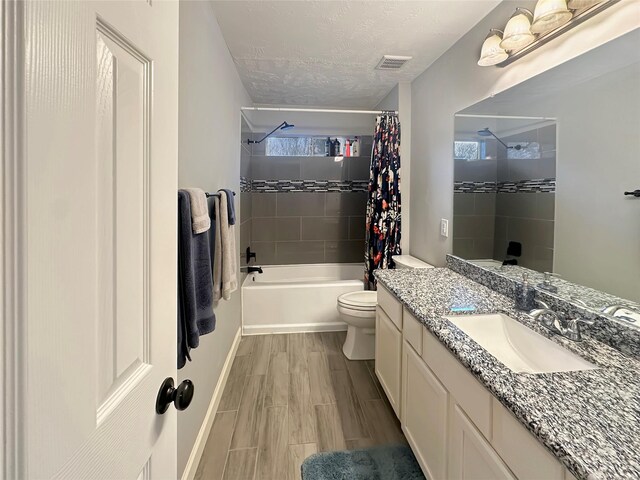 full bathroom featuring wood finish floors, toilet, vanity, shower / bath combo, and a textured ceiling