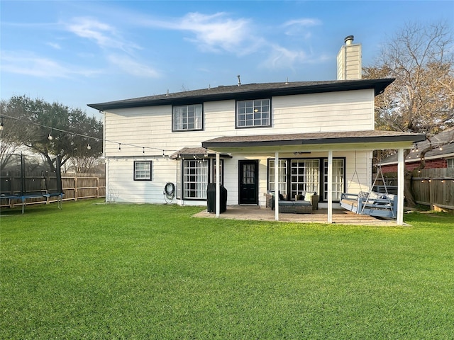 back of property with a patio area, a trampoline, a lawn, and fence