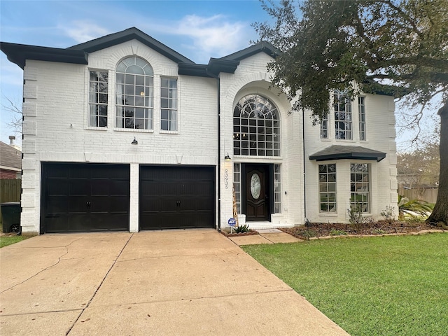 traditional-style home with a front yard, concrete driveway, brick siding, and an attached garage