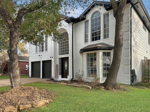 view of front of property featuring brick siding, a garage, driveway, and a front lawn