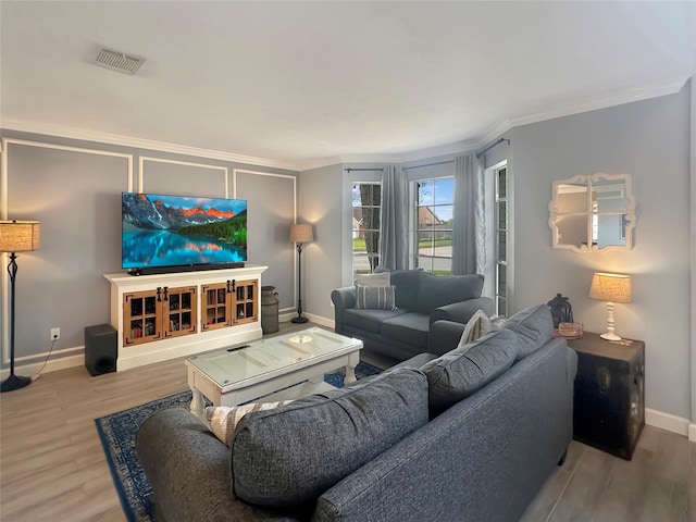 living area with crown molding, wood finished floors, visible vents, and baseboards