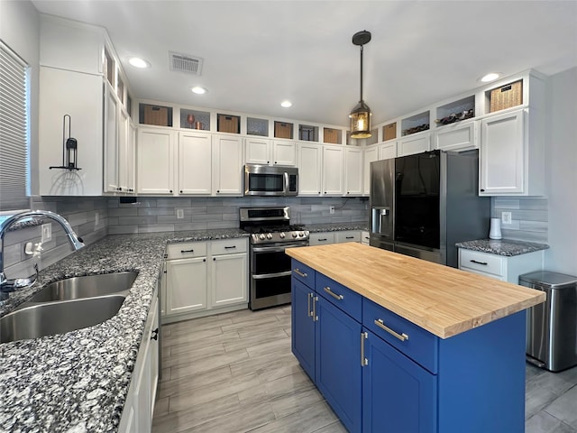 kitchen featuring visible vents, wooden counters, a sink, appliances with stainless steel finishes, and blue cabinets