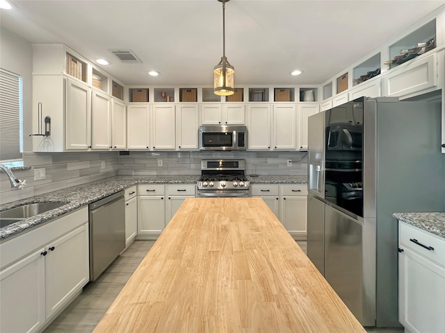 kitchen with visible vents, a sink, butcher block countertops, appliances with stainless steel finishes, and backsplash