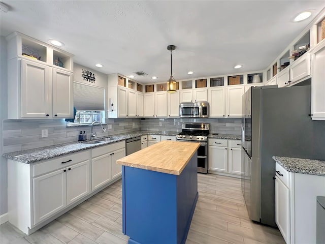 kitchen featuring visible vents, a sink, appliances with stainless steel finishes, butcher block counters, and decorative backsplash