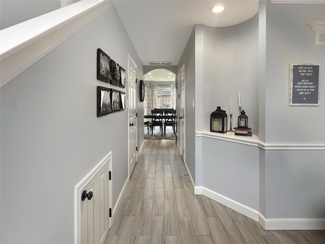 hall featuring wood finish floors, visible vents, recessed lighting, arched walkways, and baseboards