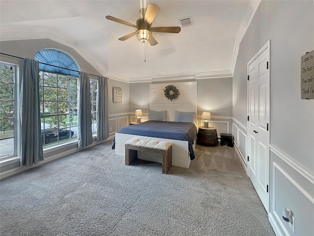 carpeted bedroom with visible vents, lofted ceiling, ornamental molding, a decorative wall, and multiple windows