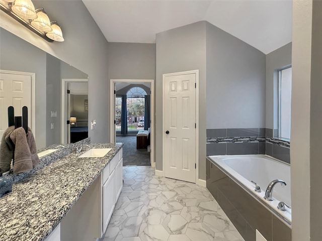 ensuite bathroom with vanity, lofted ceiling, a bath, marble finish floor, and connected bathroom