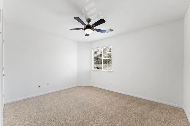 empty room featuring visible vents, light colored carpet, baseboards, and a ceiling fan