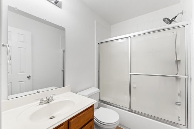 bathroom featuring combined bath / shower with glass door, toilet, and vanity