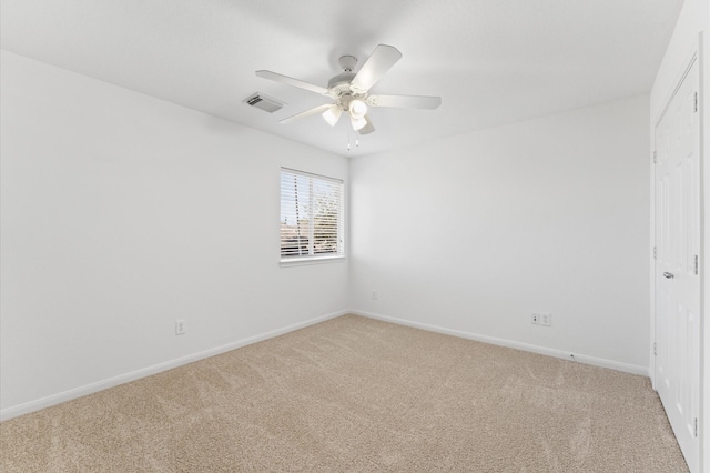 carpeted spare room featuring a ceiling fan, visible vents, and baseboards