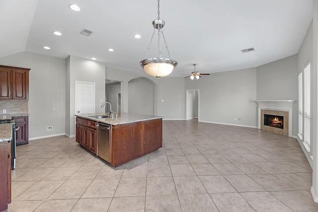 kitchen featuring visible vents, ceiling fan, appliances with stainless steel finishes, a tile fireplace, and a sink