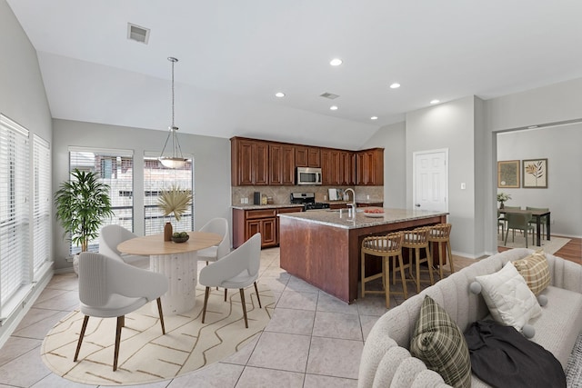 kitchen featuring lofted ceiling, light tile patterned flooring, a sink, stainless steel appliances, and tasteful backsplash