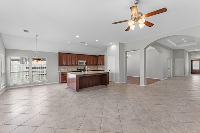 kitchen with open floor plan, stainless steel appliances, light tile patterned floors, decorative backsplash, and ceiling fan